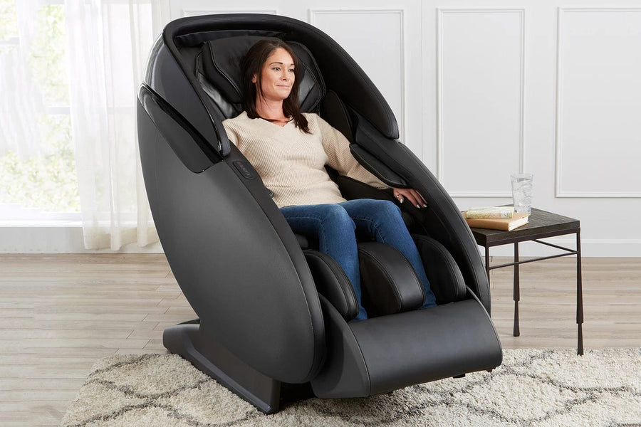 A woman sitting in a Kyota Kaizen M680 Massage Chair, experiencing a full-body massage with advanced kneading and compression features.