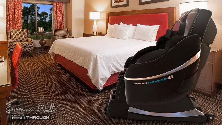 Medical Breakthrough 8 massage chair in a hotel room, featuring advanced posture correction, full-body reflexology, and customizable massage settings, positioned next to a bed with white linens.