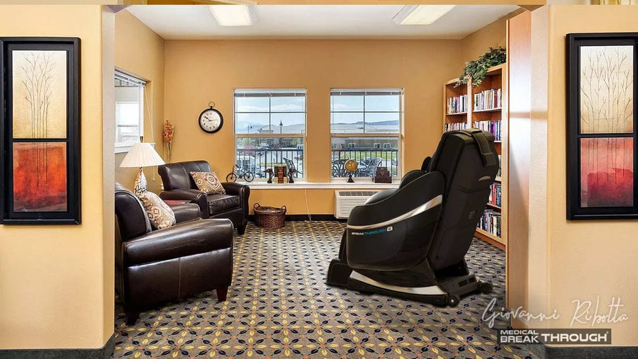 A room with a Medical Breakthrough 8 massage chair, designed to enhance posture, alleviate pain, and promote sleep, alongside a bookcase.